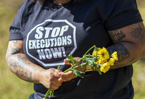 Lauren Sapp, deputy director of The Promise of Justice Initiative, helps place flowers outside Louisiana State Penitentiary in Angola, La., as supporters and faith leaders gather for Hoffman's planned execution Tuesday, March 18, 2025. Hoffman was convicted in the 1996 murder of Mary "Molly" Elliott. (Chris Granger/The Times-Picayune/The New Orleans Advocate via AP)