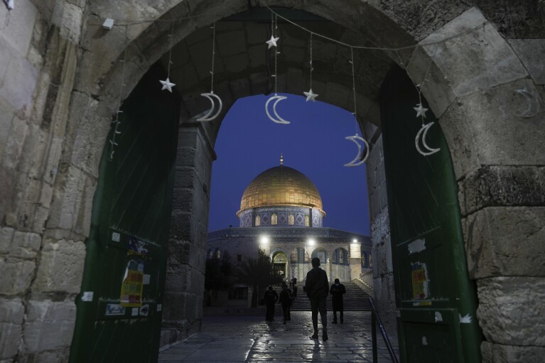 Muslims walk next to the Dome of Rock Mosque at the Al-Aqsa Mosque compound in Jerusalem's Old City, Sunday, March 10, 2024. Officials in Saudi Arabia have declared the start of the fasting month of Ramadan after sighting the crescent moon Sunday night. The announcement marks the beginning of Ramadan for many of the world's 1.8 billion Muslims. (AP Photo/Mahmoud Illean)