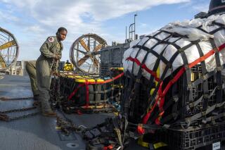 In this image released by the U.S. Navy, sailors assigned to Assault Craft Unit 4 prepare material recovered off the coast of Myrtle Beach, S.C., in the Atlantic Ocean from the shooting down of a Chinese high-altitude balloon, for transport to the FBI, at Joint Expeditionary Base Little Creek in Virginia Beach, Va., on Feb. 10, 2023. The federal government's lack of information about four aerial objects recently shot down over North America is helping to fuel conspiracy theories and conjecture on the internet. (Ryan Seelbach/U.S. Navy via AP)