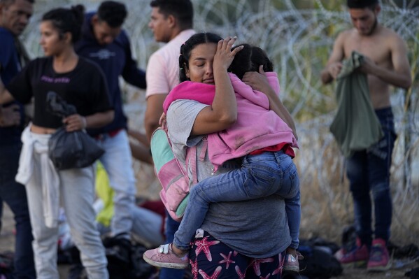 A woman carries her child after she and other migrants crossed the Rio Grande and entered the U.S. from Mexico, to be processed by U.S. Customs and Border Protection, Saturday, Sept. 23, 2023, in Eagle Pass, Texas. (AP Photo/Eric Gay)
