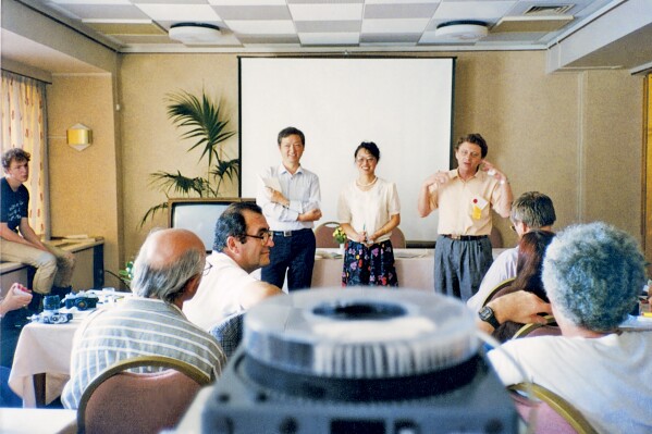 In this photo taken in August 1990 and released by Eight Light Minutes Culture, Science Fiction World editor Yang Xiao, center, stands next to next to Sichuan provincial employee Shen Zaiwang at left and American sci-fi author Norman Spinrad at right during the World Science Fiction Convention held in The Hague, Netherlands. Yang and Shen's trip to The Hague helped convince international authors it was safe to attend China's first international sci-fi authors' conference. (AP Photo/Eight Light Minutes Culture)