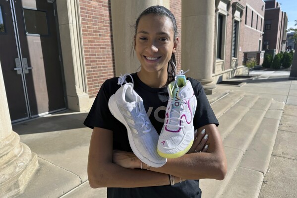 University of Nebraska volleyball player Harper Murray poses with her Avoli, right, and Adidas, left, volleyball shoes on the school campus in Lincoln, Neb., Sunday, Oct. 8, 2023. A volleyball shoe startup is bringing attention to colleges' multi-million-dollar contracts with athletic apparel companies and terms that prevent athletes from wearing other brands. Nebraska volleyball player Harper Murray is an ambassador for Avoli. (AP Photo/Eric Olson)