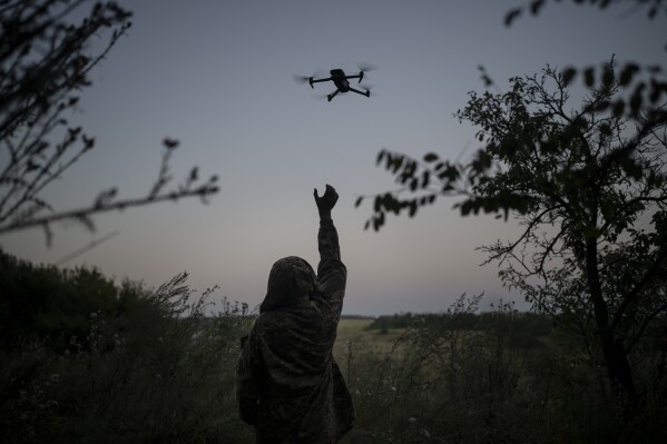 A Ukrainian drone pilot reaches for a reconnaissance drone in the Luhansk Region, Ukraine, Saturday, Aug. 19, 2023. The drone unit's task is to destroy Russia's heavy machinery, armored vehicles and infantry. (AP Photo/Bram Janssen)