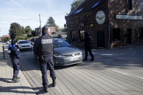 French police officers check a car near Neuville, at the France-Belgium border, Tuesday, Oct. 17, 2023 as France reinforced security at the France-Belgium border. Police in Belgium on Tuesday shot dead a suspected Tunisian extremist accused of killing two Swedish soccer fans in a brazen shooting on a Brussels street before disappearing into the night. (AP Photo/Michel Spingler)