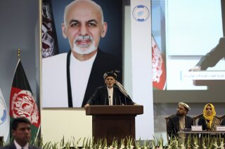 FILE - In this May 3, 2019, photo, Afghan President Ashraf Ghani speaks on the last day of the Afghan Loya Jirga meeting in Kabul, Afghanistan. Taliban officials have told The Associated Press that three Taliban prisoners released by Kabul have been flown to Qatar for a swap for an American and an Australian hostage held by the insurgents. The three Taliban prisoners were to have been freed more than one week ago by Afghan President Ashraf Ghani. (AP Photo/Rahmat Gul, File)