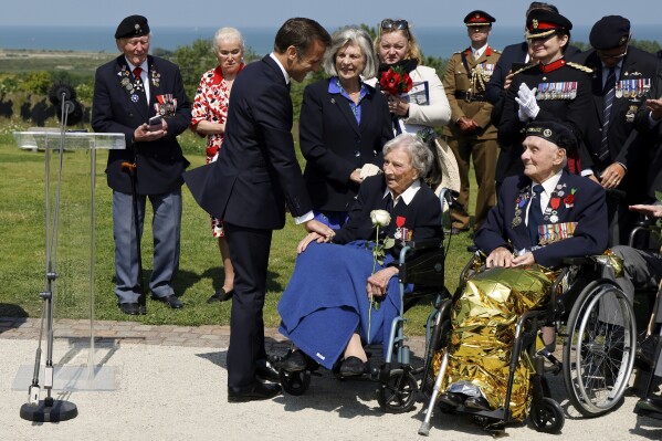 France's President Emmanuel Macron reacts after awarding 104-years-old British World War II veteran Christian Lamb, center, who helped to plan the D-Day landings in Normandy, with the insignia of Knight in the Legion of Honor order, during a commemorative ceremony marking the 80th anniversary of the World War II D-Day Allied landings in Normandy, at the World War II British Normandy Memorial of Ver-sur-Mer, Thursday, June 6, 2024. Normandy is hosting various events to officially commemorate the 80th anniversary of the D-Day landings that took place on June 6, 1944. (Ludovic Marin/Pool via AP)