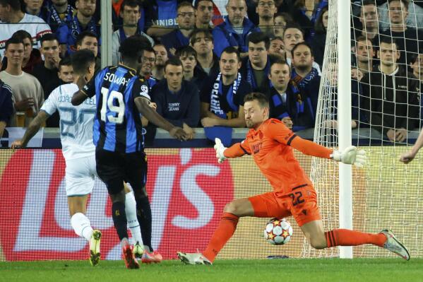 Manchester City's Joao Cancelo, left, sends the ball past Brugge's goalkeeper Simon Mignolet, right, to score the opening goal of the match during the Champions League Group A soccer match between Club Brugge and Manchester City at the Jan Breydel stadium in Bruges, Belgium, Tuesday, Oct. 19, 2021. (AP Photo/Olivier Matthys)