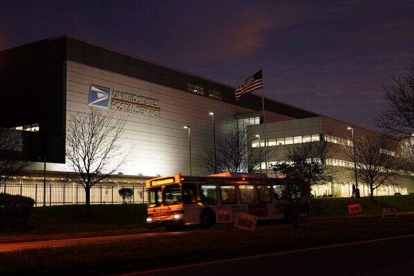 A bus drives past a United States Postal Service facility, Tuesday, Nov. 3, 2020, in Philadelphia. Concerns about mail delivery delays prompted a federal judge to order postal workers in major cities to sweep processing facilities for any remaining ballots before the end of the day. (AP Photo/Matt Slocum)