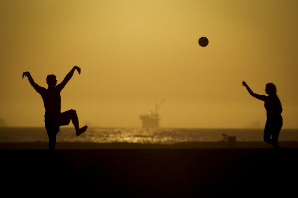 A couple plays volleyball on the sand Tuesday, April 21, 2020, in Huntington Beach, Calif. Warm temperatures are predicted for Southern California by the end of the week. (AP Photo/Chris Carlson)