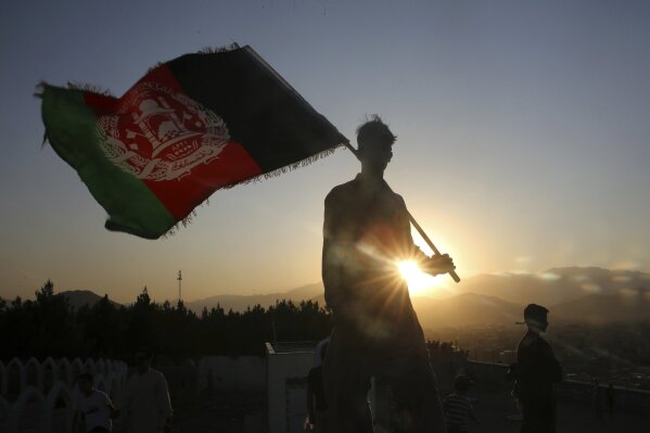 FILE - In this Aug. 19, 2019, file photo, a man waves an Afghan flag during Independence Day celebrations in Kabul, Afghanistan. An Afghan official Sunday, Feb. 9, 2020, said multiple U.S. military...