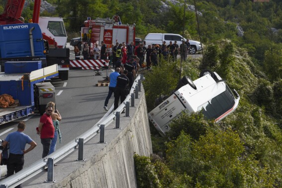 Rescue workers remove a bus at the accident site on a road near Cetinje, Montenegro, Tuesday, Sept. 19, 2023. A British national and another person were killed Tuesday and nine people were seriously injured in Montenegro when a bus plunged into a ravine, authorities said. The bus was carrying some 30 passengers when it swerved on a steep road around noon, police said. (AP Photo/Risto Bozovic)