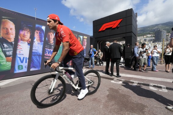 Ferrari driver Carlos Sainz of Spain bikes in the paddock ahead of the first free practice at the Monaco racetrack, in Monaco, Friday, May 24, 2024. The Formula one race will be held on Sunday. (AP Photo/Luca Bruno)