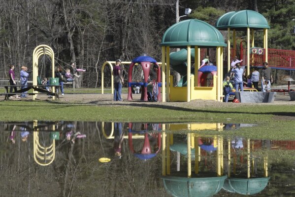 FILE - A playground at Bliss Park is reflected in standing water in this April 2, 2010, file photo in Longmeadow, Mass. Two juveniles have been arrested for allegedly dousing playground equipment in Massachusetts with acid in an incident this summer that injured four children, the Hamden District Attorney Anthony Gulluni said. (Michael S. Gordon/The Republican via AP, File)