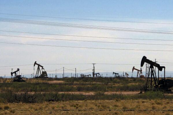 FILE - Oil rigs stand in the Loco Hills field along U.S. Highway 82 in Eddy County, near Artesia, N.M., one of the most active regions of the Permian Basin. Government budgets are booming in New Mexico. The reason behind the spending spree — oil. New Mexico is the No. 2 crude oil producer among U.S. states and the top recipient of U.S. disbursements for fossil fuel production on federal land. But a budget flush with petroleum cash has a side effect: It also puts the spotlight on how difficult it is for New Mexico and other states to turn their rhetoric on tackling climate change into reality. (AP Photo/Jeri Clausing, File)