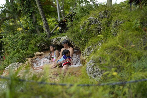 FILE - Maria Argueta, 38, cools off with her son Matthew Pastrana, 2, and niece Aurora Reyes, 10, during a cloudy day respite in the high 80s from an ongoing heat wave, at the aquifer-fed Venetian Pool in Coral Gables, Fla., July 27, 2023. (AP Photo/Rebecca Blackwell, File)