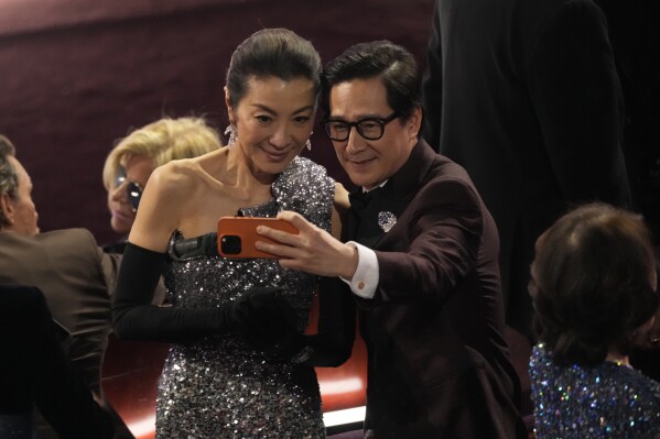 Michelle Yeoh, left, and Ke Huy Quan take a selfie during the Oscars on Sunday, March 10, 2024, at the Dolby Theatre in Los Angeles. (AP Photo/Chris Pizzello)