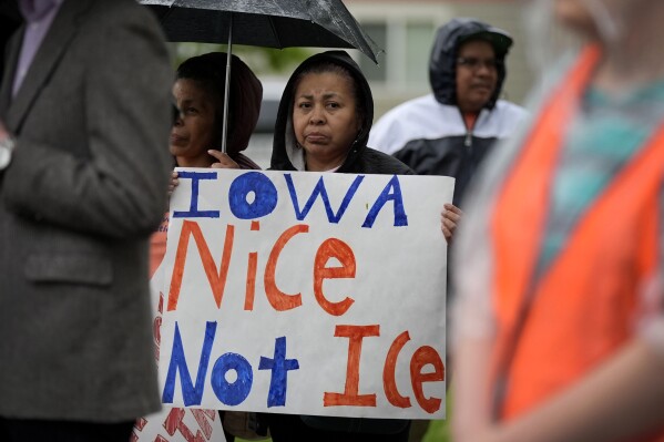FILE - A woman listens to a speaker during an Iowa Movement for Migrant Justice rally and march, Wednesday, May 1, 2024, in Des Moines, Iowa. Civil rights and immigrant rights groups Thursday, May 9, 2024, are suing Iowa over a new law that makes it a crime to be in the state if previously denied admission to the U.S. (AP Photo/Charlie Neibergall, File)