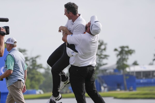 Shane Lowry, of Ireland, hoists up teammate Rory McIlroy, of Northern Ireland, after they won the PGA Zurich Classic golf tournament at TPC Louisiana in Avondale, La., Sunday, April 28, 2024. (AP Photo/Gerald Herbert)