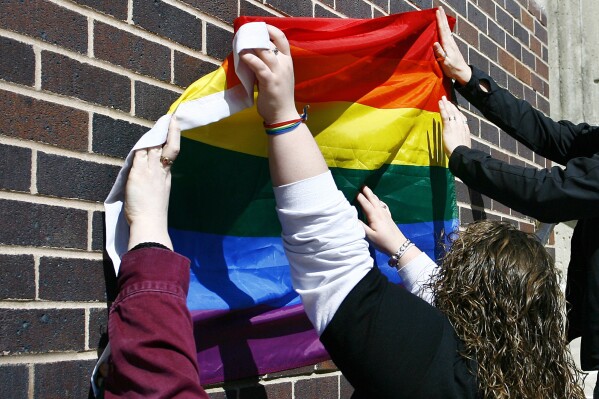 FILE - University of Northern Iowa students up a rainbow flag before a Gay Marriage Rally at Mauker Union on the University of Northern Iowa campus, Friday, April 3, 2009, in Cedar Falls, Iowa. The Iowa Supreme Court affirmed the hate crime conviction Friday, Dec. 1, 2023, of a man who posted hand-written notes at homes with rainbow flags and emblems, urging them to “burn that gay flag.” (Matthew Putney/The Courier via AP, File)