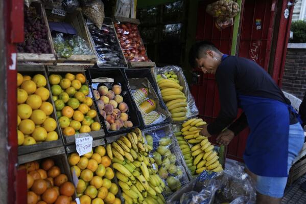 A produce vendor arranges bananas at his store in Buenos Aires, Argentina, Monday, April 14, 2025. (AP Photo/Natacha Pisarenko)