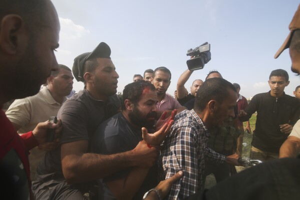 Palestinians transport a captured Israeli civilian, center, from Kibbutz Kfar Azza into the Gaza Strip on Saturday, Oct. 7, 2023. The militant Hamas rulers of the Gaza Strip carried out an unprecedented, multi-front attack on Israel at daybreak Saturday, firing thousands of rockets as dozens of Hamas fighters infiltrated the heavily fortified border in several locations by air, land, and sea and catching the country off-guard on a major holiday. (AP Photo/Hatem Ali)