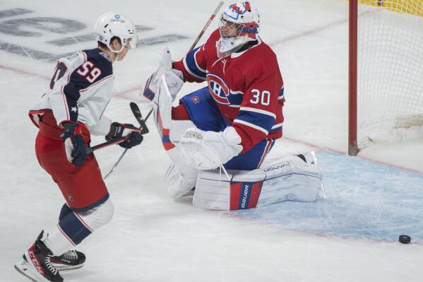 Columbus Blue Jackets' Yegor Chinakhov, left, scores against Montreal Canadiens goaltender Caydem Primeau (30) during first-period NHL hockey game action in Montreal, Sunday, Jan. 30, 2022. (Graham Hughes/The Canadian Press via AP)