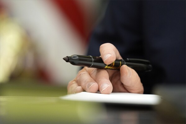President Donald Trump holds a pen as he signs executive orders in the Oval Office of the White House, Monday, Jan. 20, 2025, in Washington. (AP Photo/Evan Vucci)