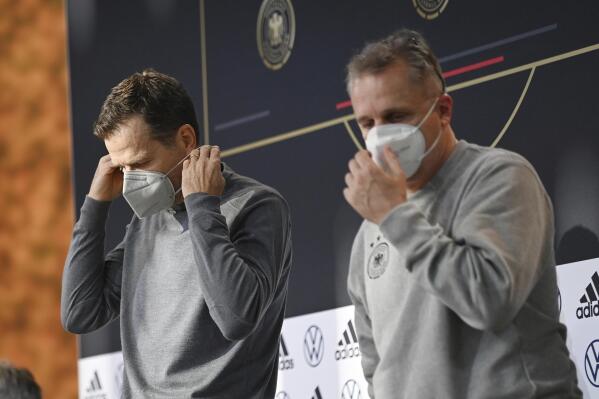 DFB director Oliver Bierhoff, left, and DFB doctor Tim Meyer leave a press conference wearing mouth-nose protection in Wolfsburg, Germany, prior the World Cup qualifying match against Liechtenstein, Tuesday, Nov. 9, 2021. There is said to be a positive Corona case in the national football team circle. National coach Hansi Flick cancelled the planned training in the morning at the stadium in Wolfsburg. Five players have to be quarantined in Wolfsburg. (Swen Pfoertner/dpa via AP)