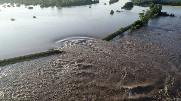 In this aerial image provided by Yell County Sheriff's Department water rushes through the levee along the Arkansas River Friday, May 31, 2019, in Dardanelle, Ark. Officials say the levee breached early Friday at Dardanelle, about 60 miles northwest of Little Rock.  (Yell County Sheriff's Department via AP)