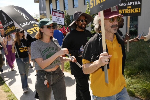 Marc Maron, right, Hannah Einbinder, from second left, and Debby Ryan walk on a picket line outside Netflix studios on Friday, July 21, 2023, in Los Angeles. The actors strike comes more than two months after screenwriters began striking in their bid to get better pay and working conditions. (AP Photo/Chris Pizzello)