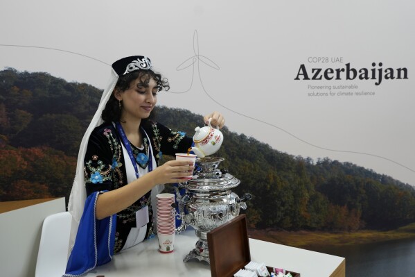 A woman pours tea at the Azerbaijan Pavilion at the COP28 U.N. Climate Summit, Sunday, Dec. 10, 2023, in Dubai, United Arab Emirates. (AP Photo/Rafiq Maqbool)