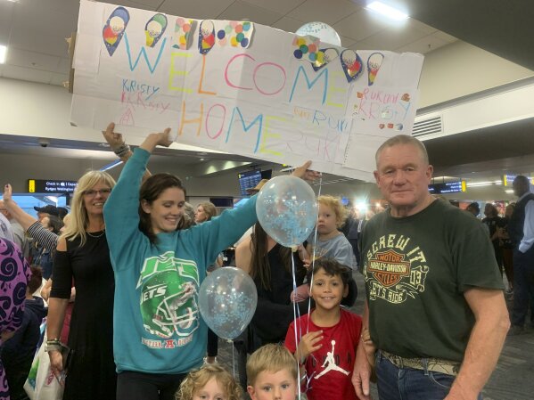 Danny Mather, right, and other family members wait at the Wellington International Airport for the arrival of Mather's pregnant daughter Kristy in Wellington, New Zealand Monday, April 19, 2021. The start of quarantine-free travel was a relief for families who have been separated by the coronavirus pandemic as well as to struggling tourist operators. (AP Photo/Nick Perry)