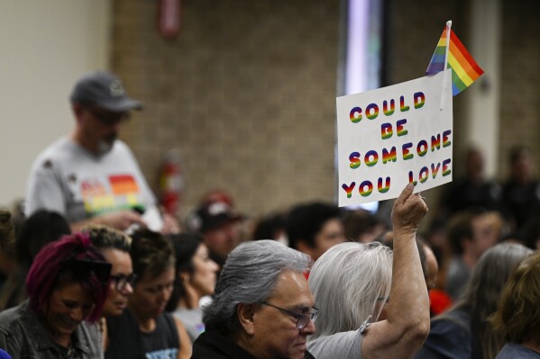 FILE - Parents, students, and staff of Chino Valley Unified School District hold up flags and signs in favor of protecting LGBTQ+ policies at the school board meeting held at Don Antonio Lugo High School on June 15, 2023, in Chino, Calif. Parts of a controversial Southern California school district policy that require school staff to tell parents if their child asks to change their gender identity will remain halted after a judge granted a preliminary injunction Thursday, Oct. 18, 2023, to block them until a final decision is made in the case. (Anjali Sharif-Paul/The Orange County Register via AP, File)