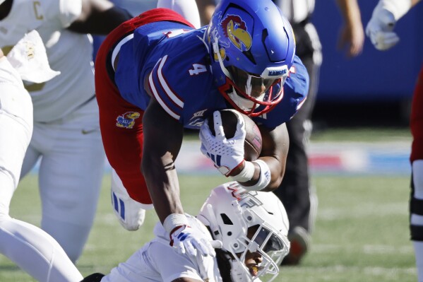Kansas running back Devin Neal (4) is brought down by Central Florida defensive back Demari Henderson (8) after rushing for a first down during the first half of an NCAA college football game Saturday, Oct. 7, 2023, in Lawrence, Kan. (AP Photo/Colin E. Braley)