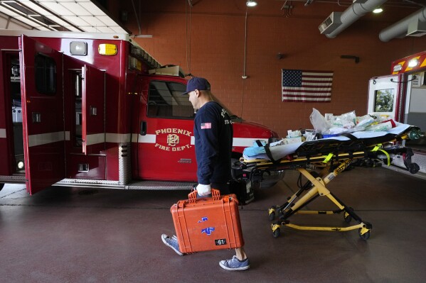 Phoenix Fire Department firefighter John Cooley walks with gear inside Phoenix Fire Department Station 61 as temperatures are expected to hit 116-degrees Tuesday, July 18, 2023, in Phoenix. The extreme heat scorching Phoenix set a record Tuesday, the 19th consecutive day temperatures hit at least 110 degrees Fahrenheit (43 Celsius) in a summer of suffering that's echoing around much of the globe. (AP Photo/Ross D. Franklin)
