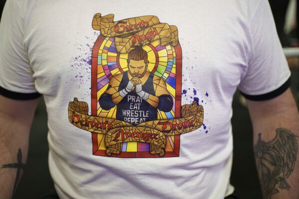 Se ve un detalle en la camiseta de Gareth "Angel" Thompson, fundador de la organización benéfica Kingdom Wrestling, en la iglesia de St Peter en Shipley, después de uno de los espectáculos mensuales de lucha libre de la organización, el sábado 29 de marzo de 2025. (Foto AP/Jon Super)