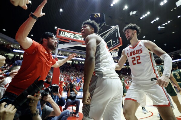 New Mexico guard Donovan Dent, center, celebrates with fans and Mustapha Amzil (22) after scoring the game-winning basket against Colorado State in an NCAA college basketball game, Wednesday, Feb. 21, 2024, in Albuquerque, N.M. (APPhoto/Eric Draper)