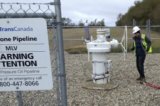 In this Oct. 11, 2016 photo provided by Samuel Jessup, climate change activist Michael Foster, of Seattle, turns an emergency shut-off valve on an oil pipeline in northeastern North Dakota. Foster was arrested and ended up spending six months in jail. The valve-turning tactic has been embraced in recent years by activists who believe fossil fuels are precipitating a global warming crisis. But the energy industry and its advocates say it amounts to domestic terrorism, and lawmakers in several states are considering stiffening penalties. (Courtesy of Samuel Jessup via AP)