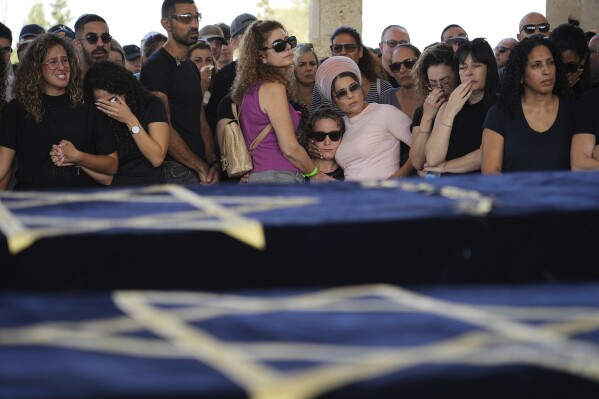 Mourners gather around the coffins of Gil Taasa and his son Or during their funeral in Kibbutz Nitzan, Israel, Wednesday, Oct. 18, 2023. The father and his son were killed by Hamas militants on Oct. 7 in Netiv Haasara, close to the Gaza Strip's separation fence with Israel. (AP Photo/Tsafrir Abayov)