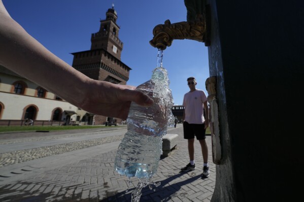 FILE - Tourists fill plastic bottles with water from a public fountain at the Sforzesco Castle, in Milan, Italy, June 25, 2022. A new study found the average liter of bottled water has nearly a quarter million invisible pieces of nanoplastics, microscopic plastic pieces, detected and categorized for the first time by a microscope. (AP Photo/Luca Bruno, File)
