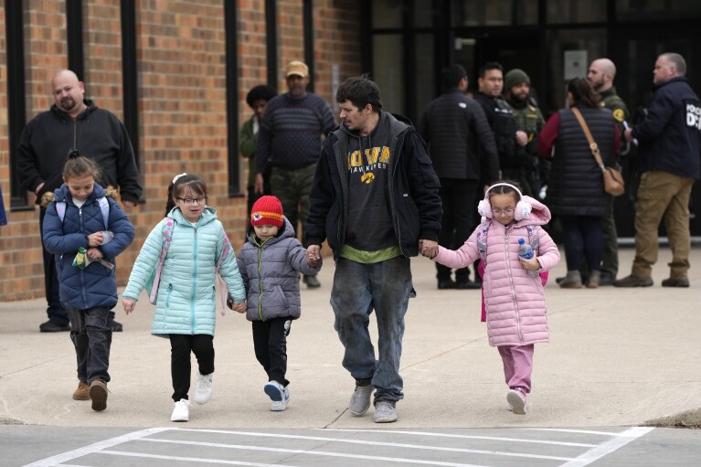 A man and children leave the McCreary Community Building after being reunited following a shooting at Perry High School, Thursday, Jan. 4, 2024, in Perry, Iowa. (AP Photo/Charlie Neibergall)