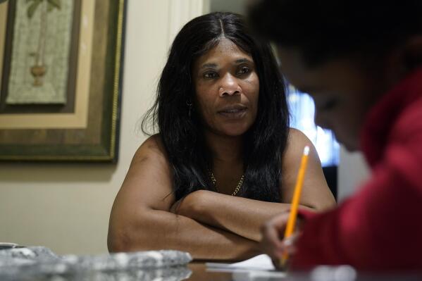 Evena Joseph, left, sits with her son J. Ryan Mathurin, 9, as he does his homework, Thursday, Dec. 22, 2022, at their home, in Boston. (APPhoto/Steven Senne)
