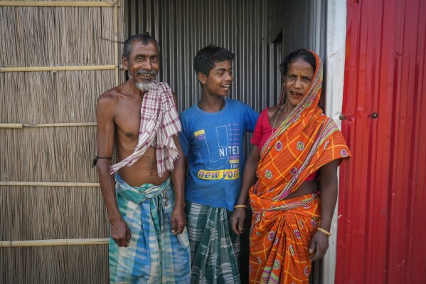 Indian voters Yaad Ali, left, and his wife Monuwara Begum, right, and his son Musikur Alam stand outside their house in Sandahkhaiti, a floating island village in the Brahmaputra River on the eve of the second phase of the national election in Morigaon district, Assam, India, Thursday, April 25, 2024. "All the politicians promise to solve problems related to flooding but after elections are over, no one cares about it," Ali said. (AP Photo/Anupam Nath)