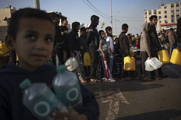 Palestinians line up for water in the Muwasi area in the south of the Gaza Strip on Monday, Dec. 18, 2023. (AP Photo/Fatima Shbair)