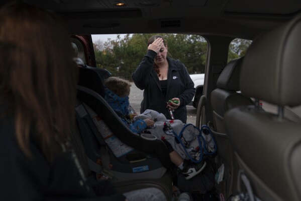 Jesse Johnson pauses before closing the van door after shopping for Halloween costumes with her children at Spirit Halloween in Findlay, Ohio, Friday, Oct. 20, 2023. (AP Photo/Carolyn Kaster)