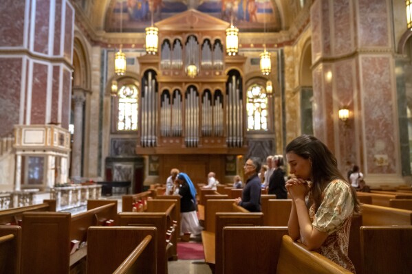 Members of the faithful pray during midday services at St. Matthew's Cathedral on Thursday, May 8, 2025, in Washington, after white smoke emanated from a chimney at the Vatican where 133 cardinals are gathering on the second day of a conclave to elect a successor to late Pope Francis. (AP Photo/Mark Schiefelbein)