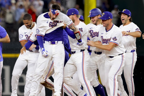 Texas Rangers' Jonah Heim, front left, and teammates celebrate Heim's single that drove in the winning against the Chicago Cubs in the 10th inning of a baseball game Thursday, March 28, 2024 in Arlington, Texas. (AP Photo/Gareth Patterson)