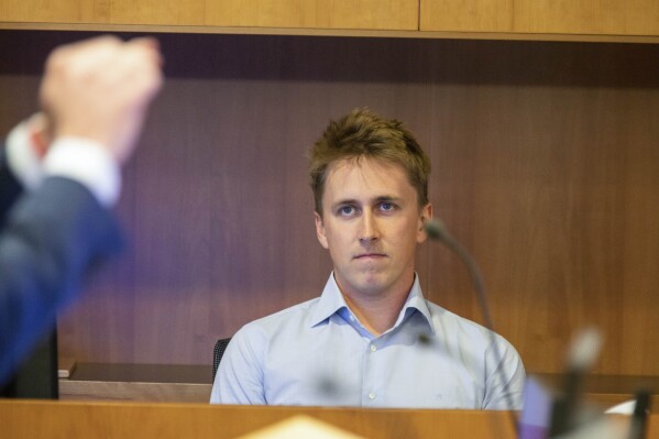 Pilot Brian Depauw reacts in the witness box at the Whakaari White Island eruption trial at the Auckland Environment Court, in Auckland, New Zealand, Thursday July 13, 2023. Depauw, a helicopter pilot said Thursday he and two of his passengers had escaped serious injury by jumping into the ocean when a New Zealand volcano erupted in 2019, killing 22. (Nick Monro/Pool Photo via AP)