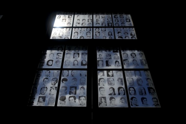 Photographs of people who disappeared during Argentina's dictatorship fill a window at the Museum of Space for Memory and the Promotion and Defense of Human Rights (ESMA) in Buenos Aires, Argentina, Tuesday, March 19, 2024. The ESMA was once the Navy School of Mechanics and housed the most infamous illegal detention center during the dictatorship. (AP Photo/Natacha Pisarenko)
