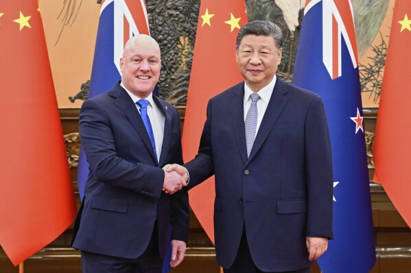 In this photo released by Xinhua News Agency, visiting New Zealand's Prime Minister Christopher Luxon, left shakes hands with Chinese President Xi Jinping prior to their bilateral meeting in Beijing, Friday, June 20, 2025. (Shen Hong/Xinhua via AP)